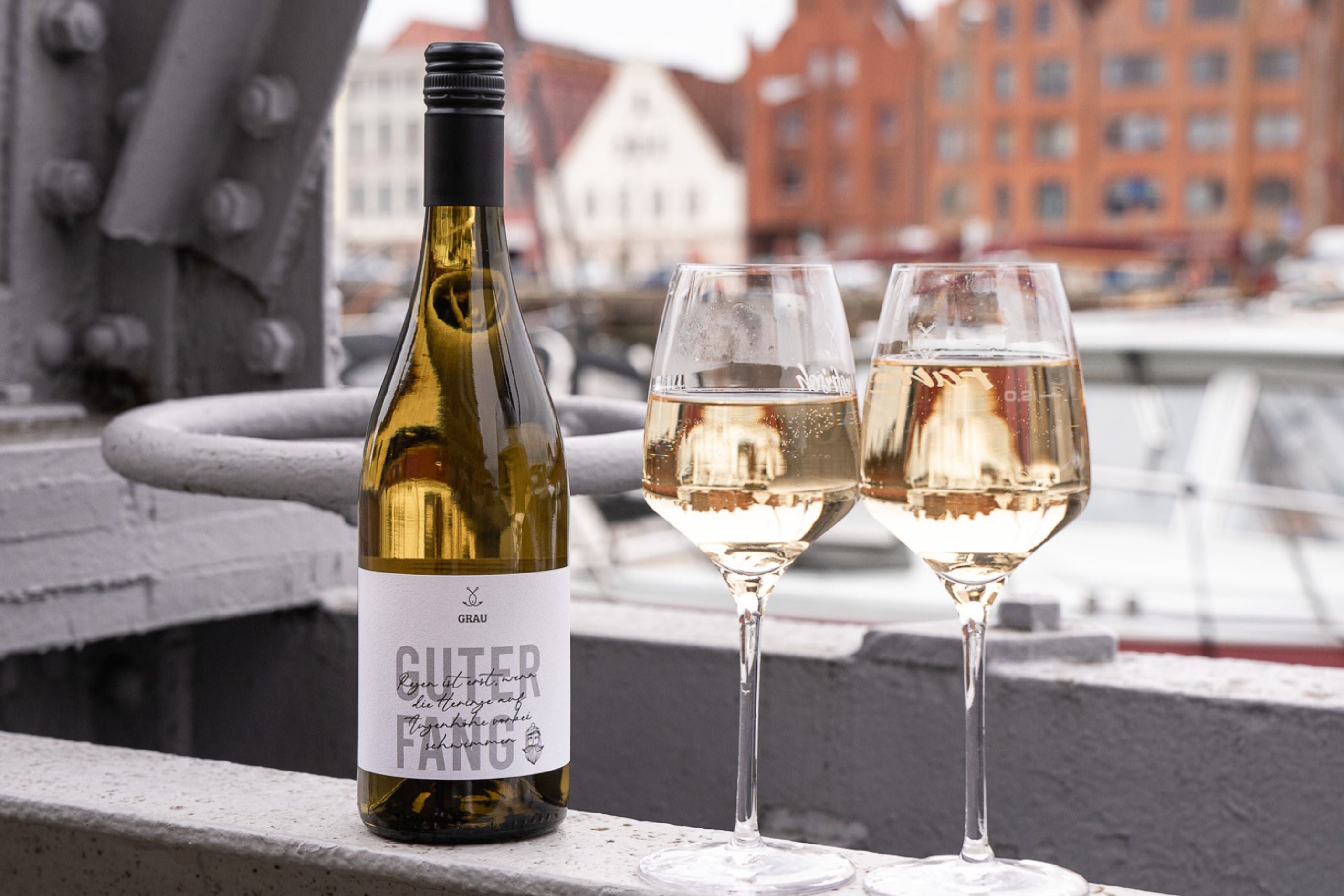 Guter Fang Weißweinflasche neben Weißwein Gläsern mit Lübecker Alstadt im Himtergrund