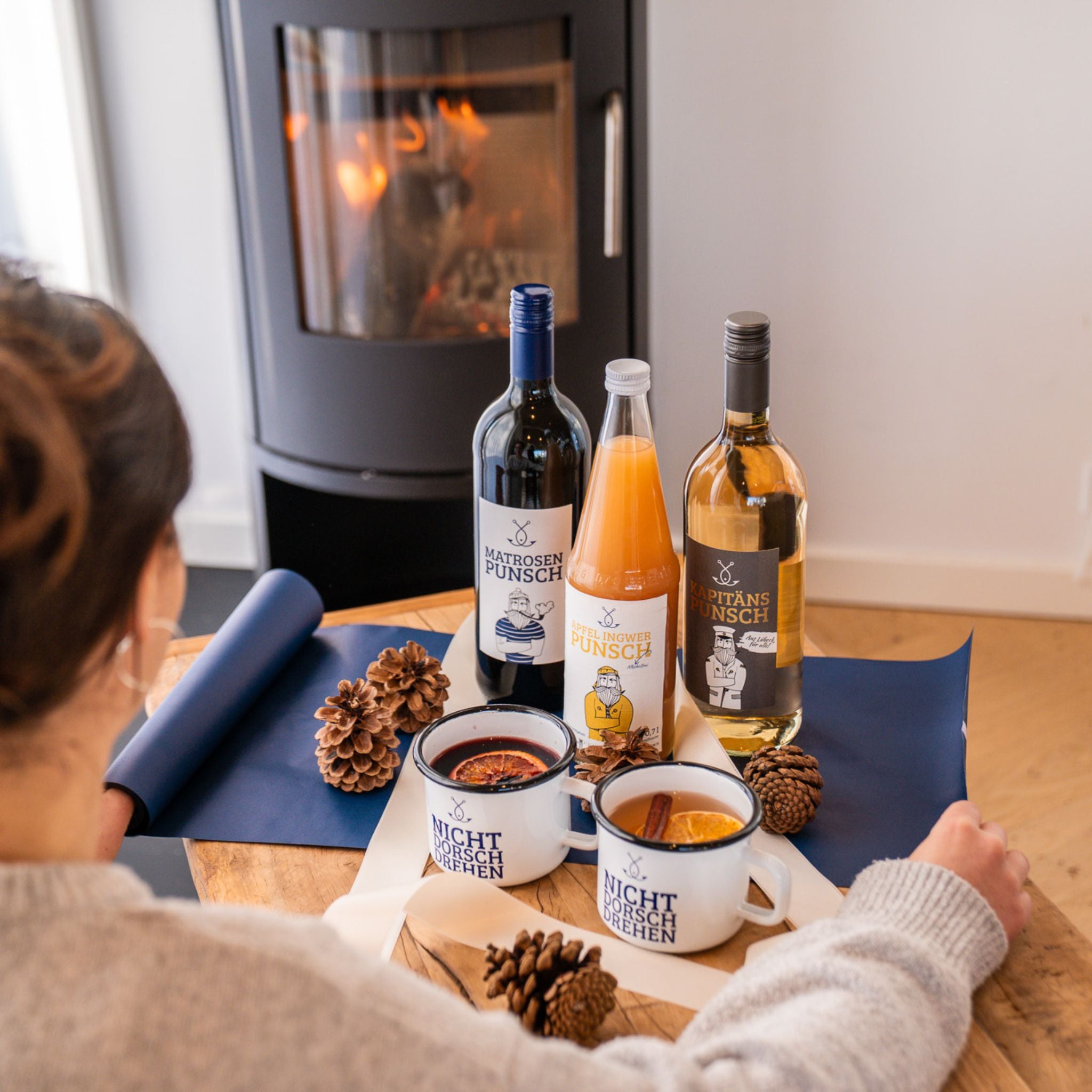 Geschenkset mit Glühwein und Punsch vor Kamin, gemütliche Winterstimmung