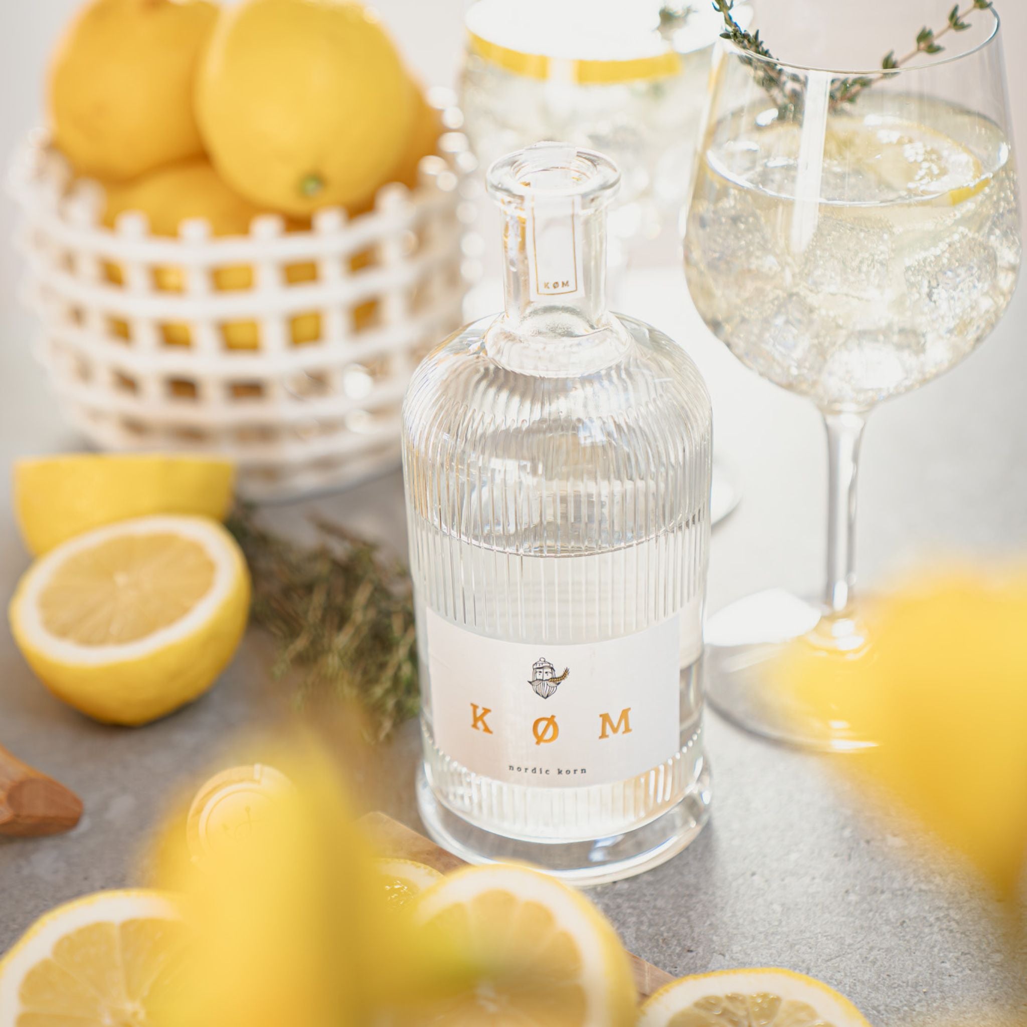 KØM Nordic Korn Flasche mit Zitronen und Drink im Glas, sommerliche Szene