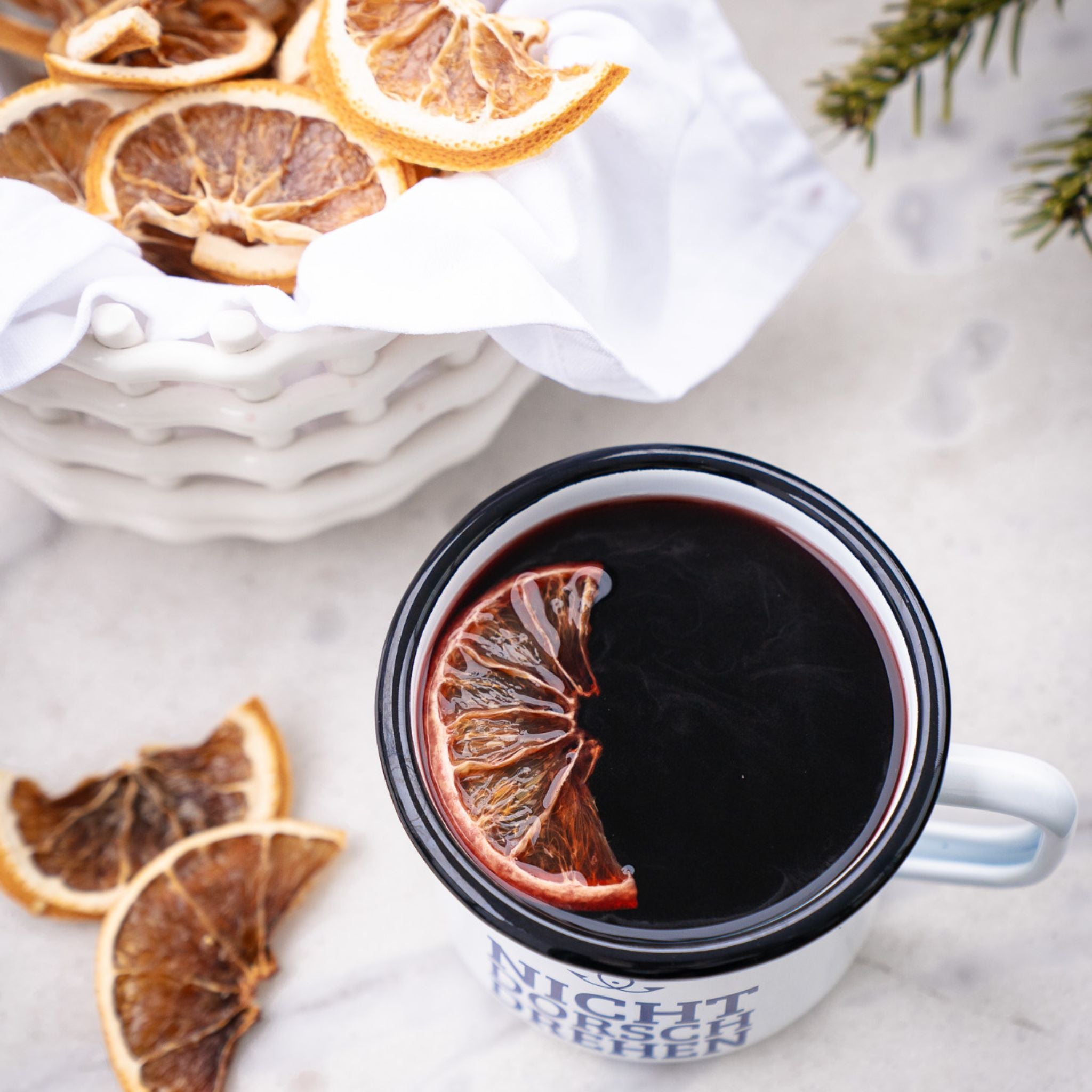 Tasse mit heißem Matrosenpunsch und Orangenscheibe, winterliche Stimmung mit getrockneten Zitrusfrüchten