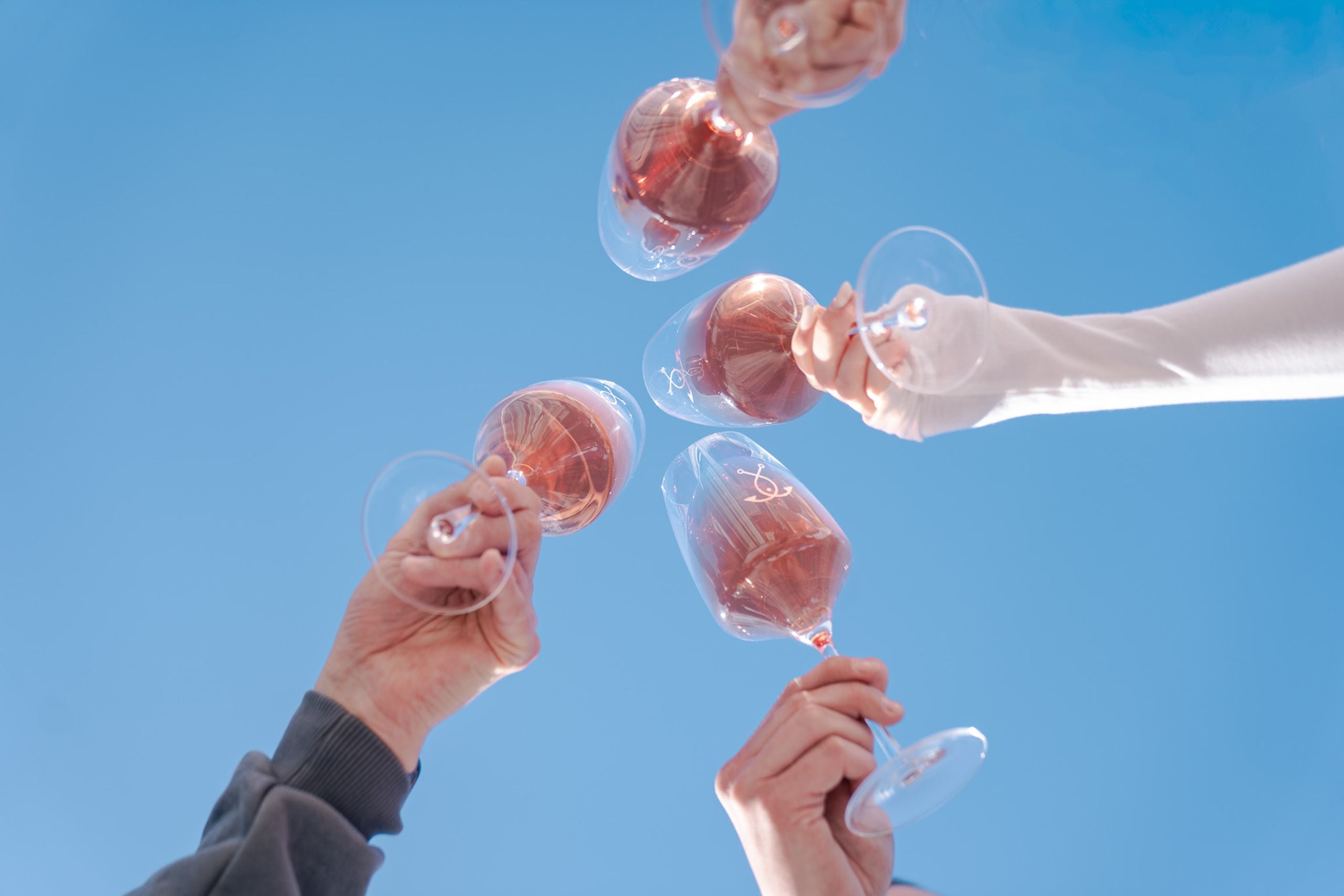 Rosé Wein Gläser stoßen an – Sommermoment unter blauem Himmel