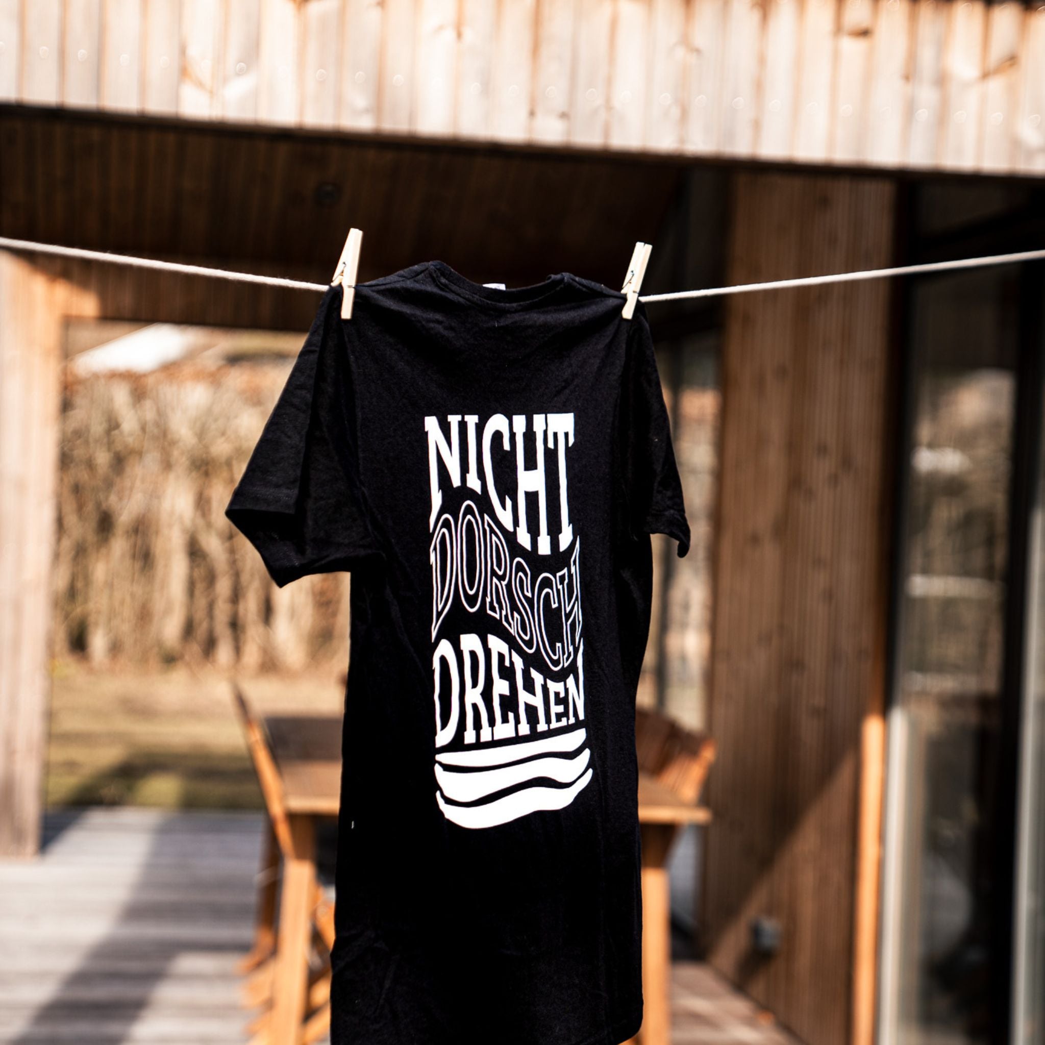 T-Shirt NICHT DORSCHDREHEN auf Wäscheleine – schwarzes Baumwollshirt mit großem Backprint