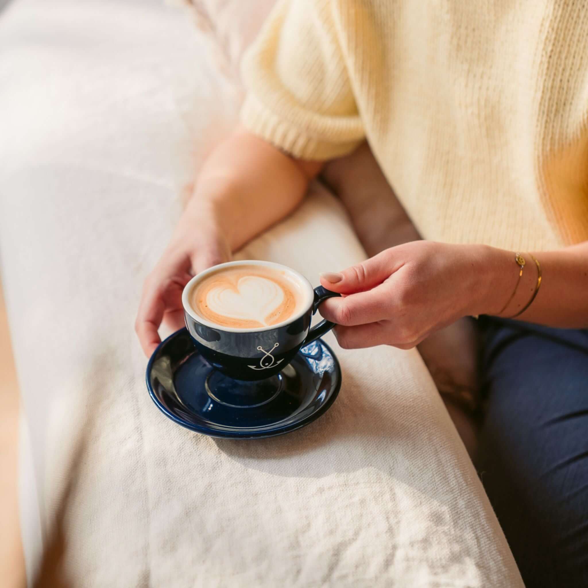 Cappuccino Tasse dunkelblau in der Hand – Latte Art Detail