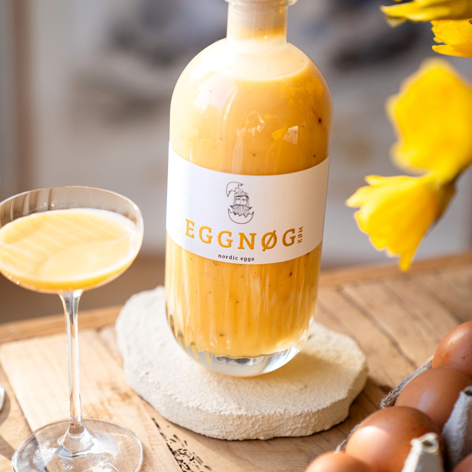EGGNØG KØM Eierlikör Flasche mit Glas und Frühlingsblumen