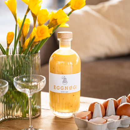 EGGNØG KØM Eierlikör Flasche mit Glas und Frühlingsblumen
