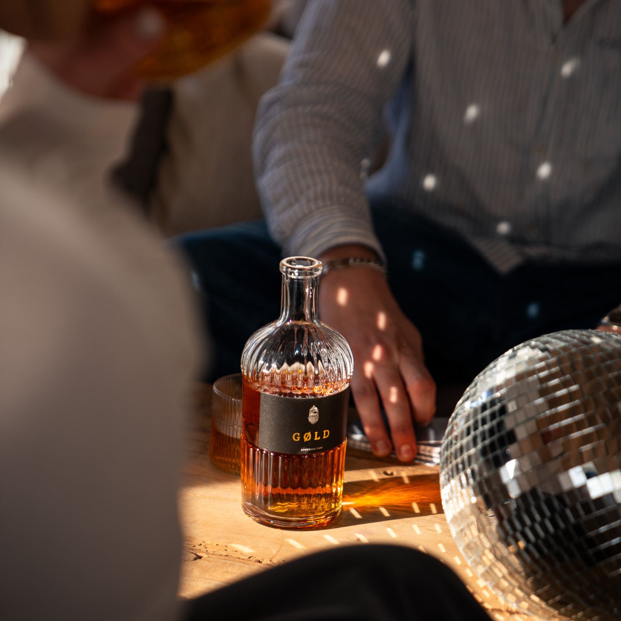 GØLD Overseas Rum Flasche  neben einer Diskokugel und Sonnenlicht