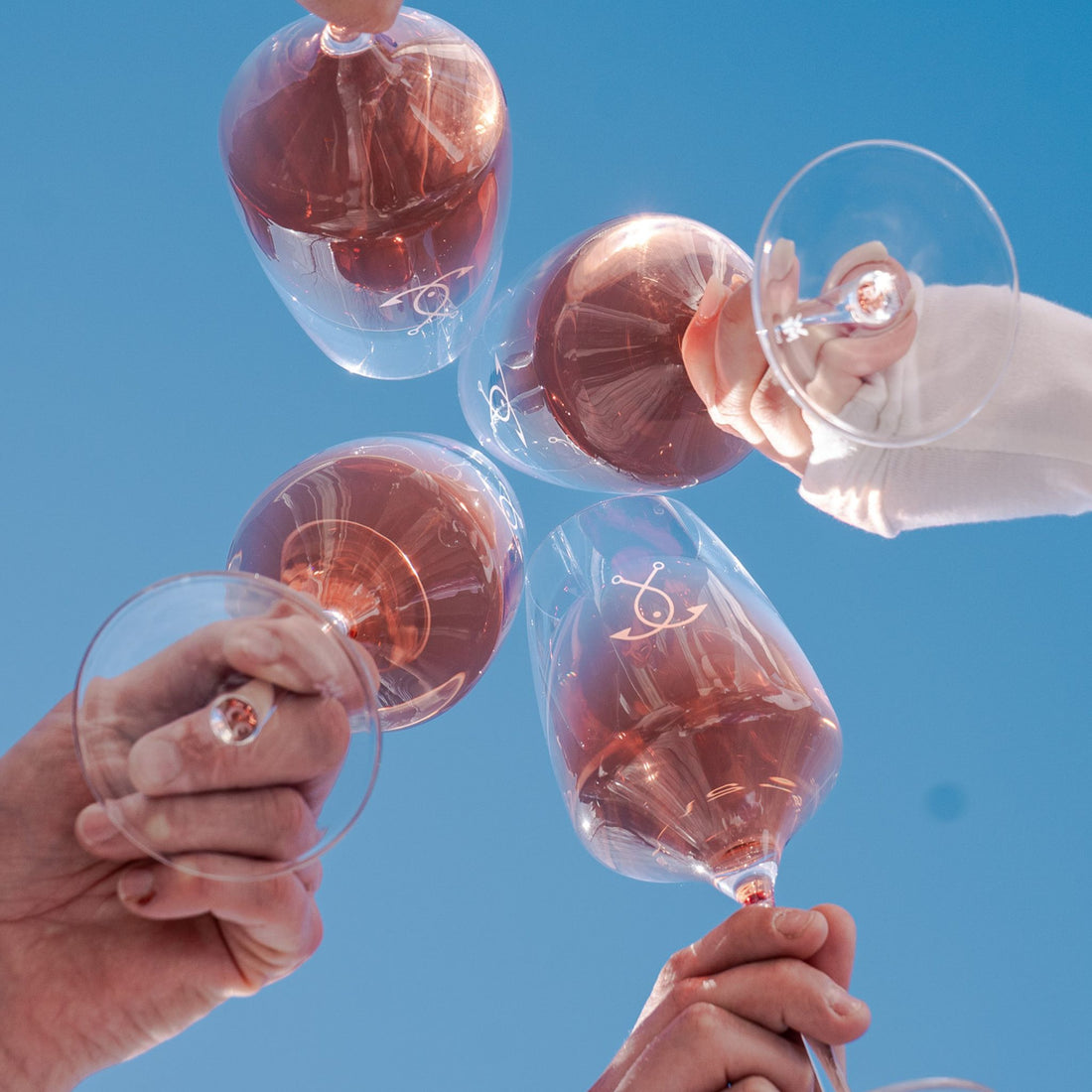 Guter Fang Rosé Wein Gläser stoßen an – Sommermoment unter blauem Himmel