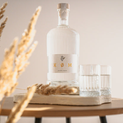 KØM Nordic Korn Flasche auf Holztablett mit zwei Gläsern im warmen Licht