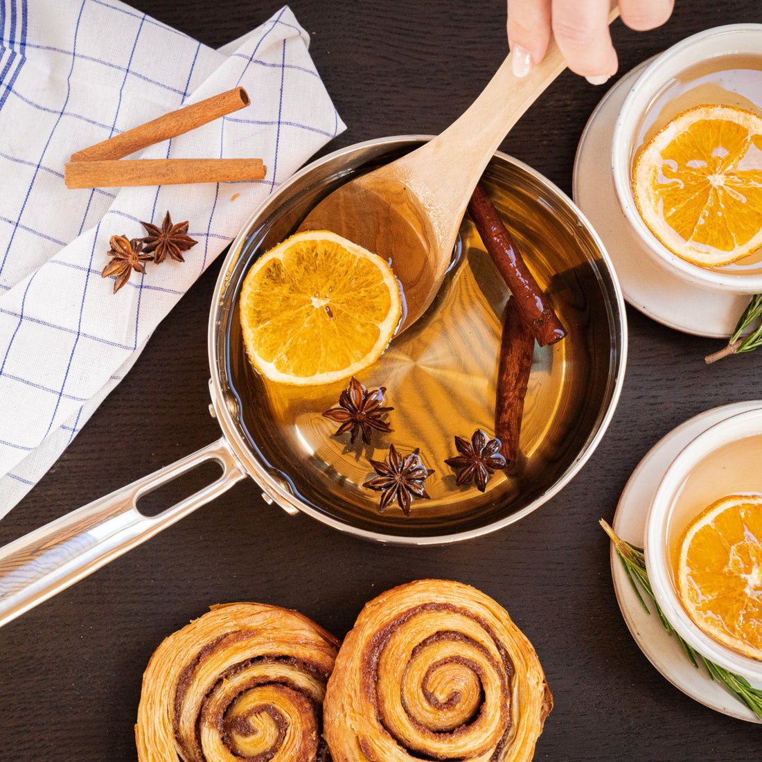 Topf mit weißem Kapitänspunsch Glühwein, Orange und Gewürzen sowie Gebäck auf Tisch