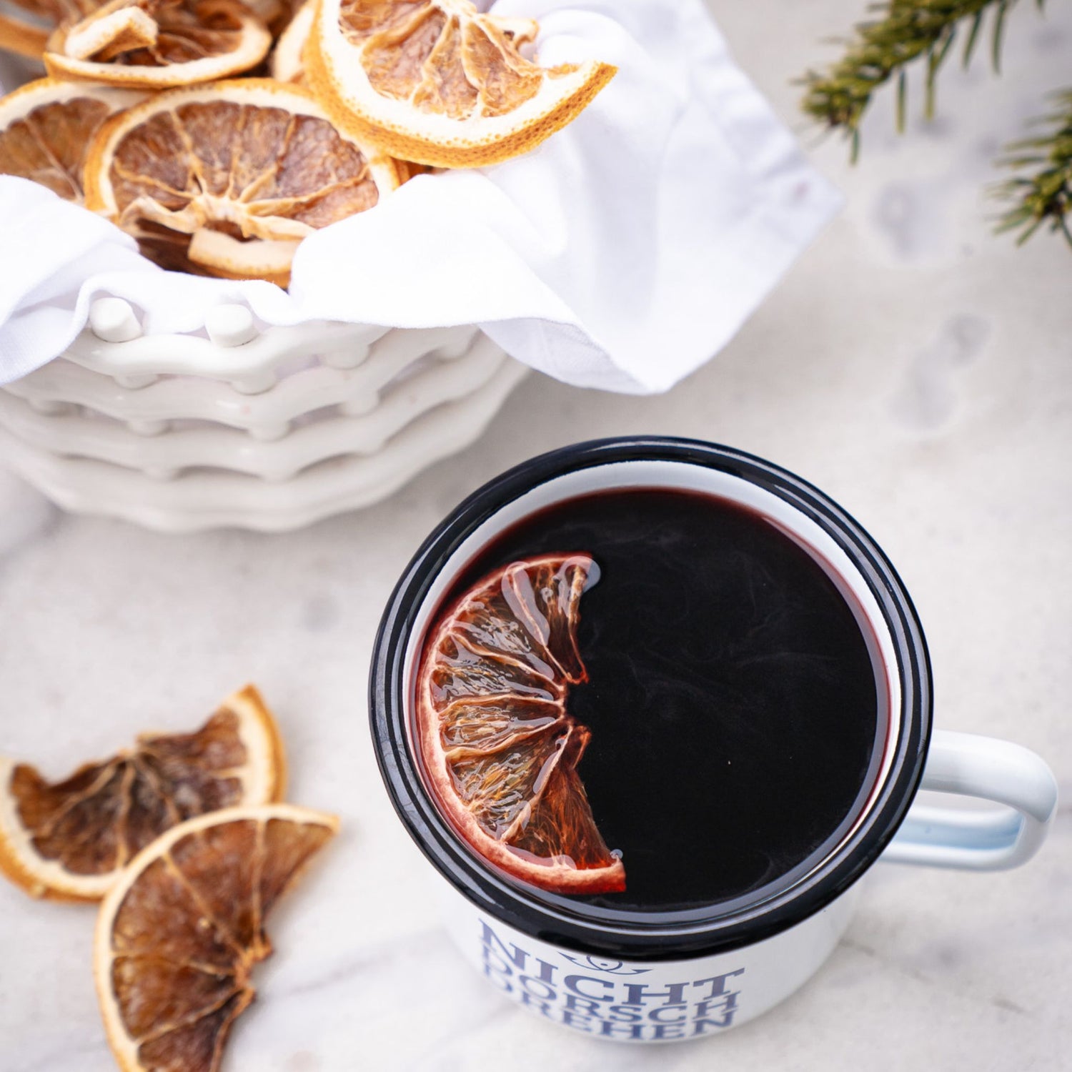 Tasse mit heißem Matrosenpunsch und Orangenscheibe, winterliche Stimmung mit getrockneten Zitrusfrüchten