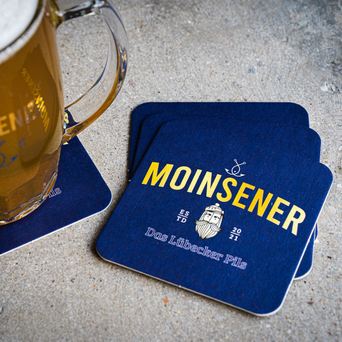 Moinsener Bierdeckel mit Bierkrug auf Holztisch