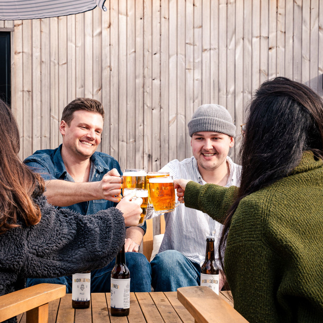 Moinsener Bierkrug beim Anstoßen in geselliger Runde draußen