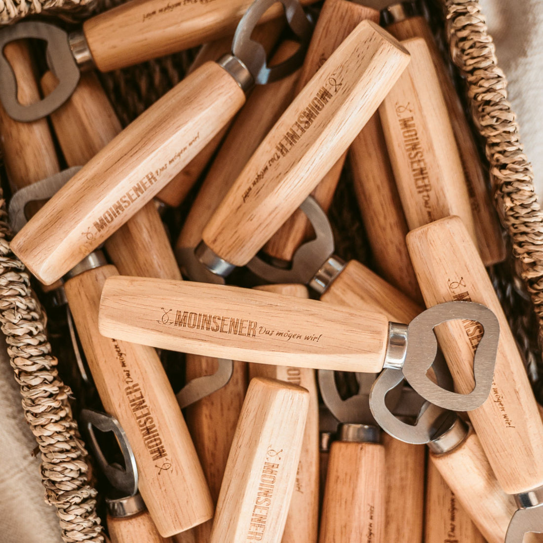 Moinsener Flaschenöffner aus Holz mit Gravur in einem Korb mit mehreren Öffnern