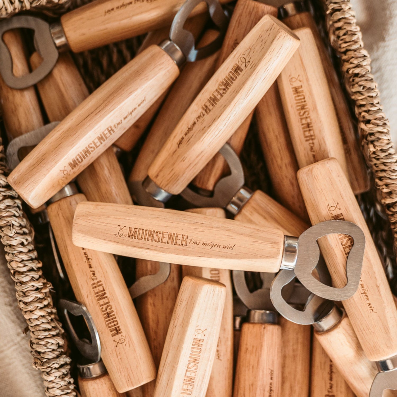 Moinsener Flaschenöffner aus Holz mit Gravur in einem Korb mit mehreren Öffnern