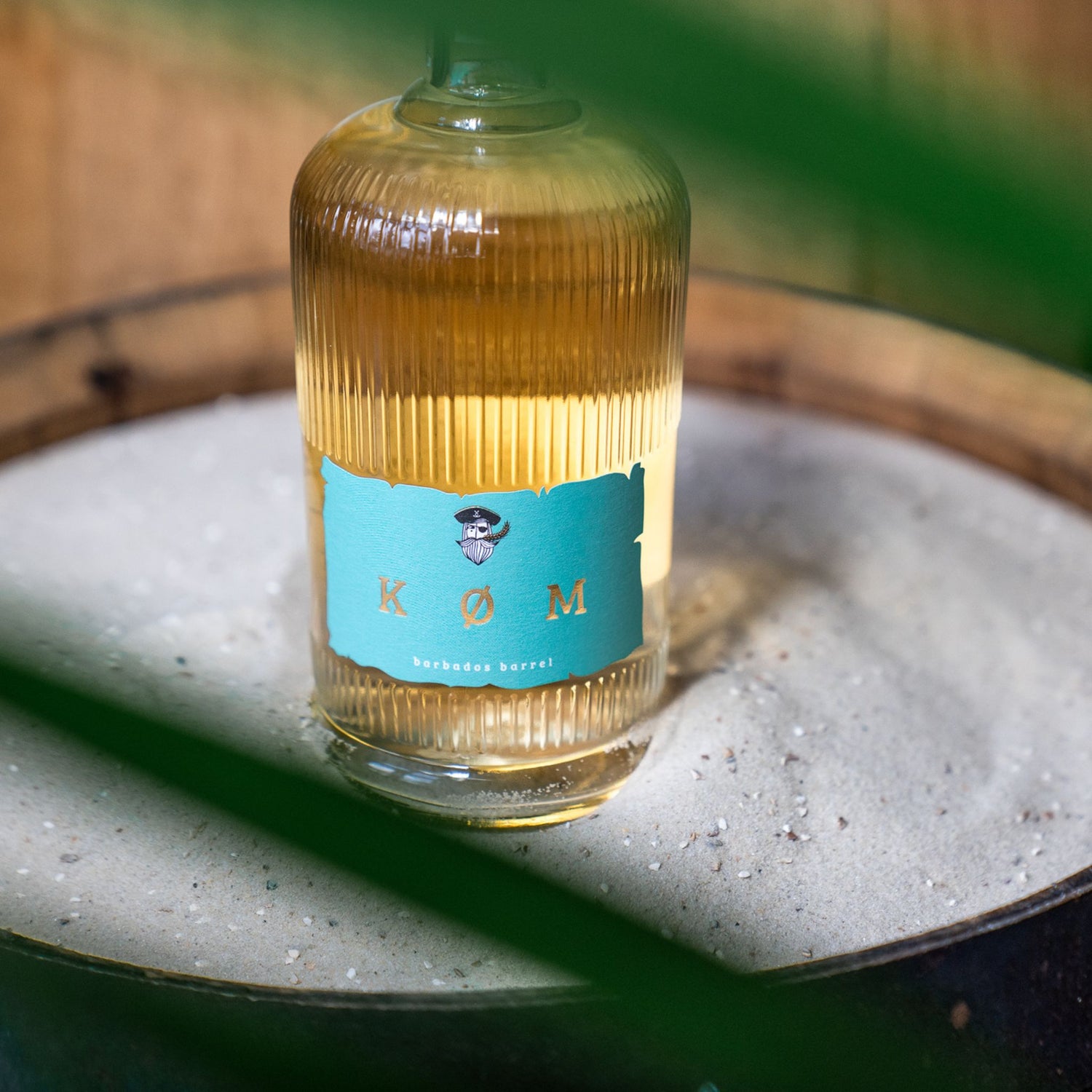 Eine Flasche KØM BARBADOS BARRELL steht im Ostseesand 