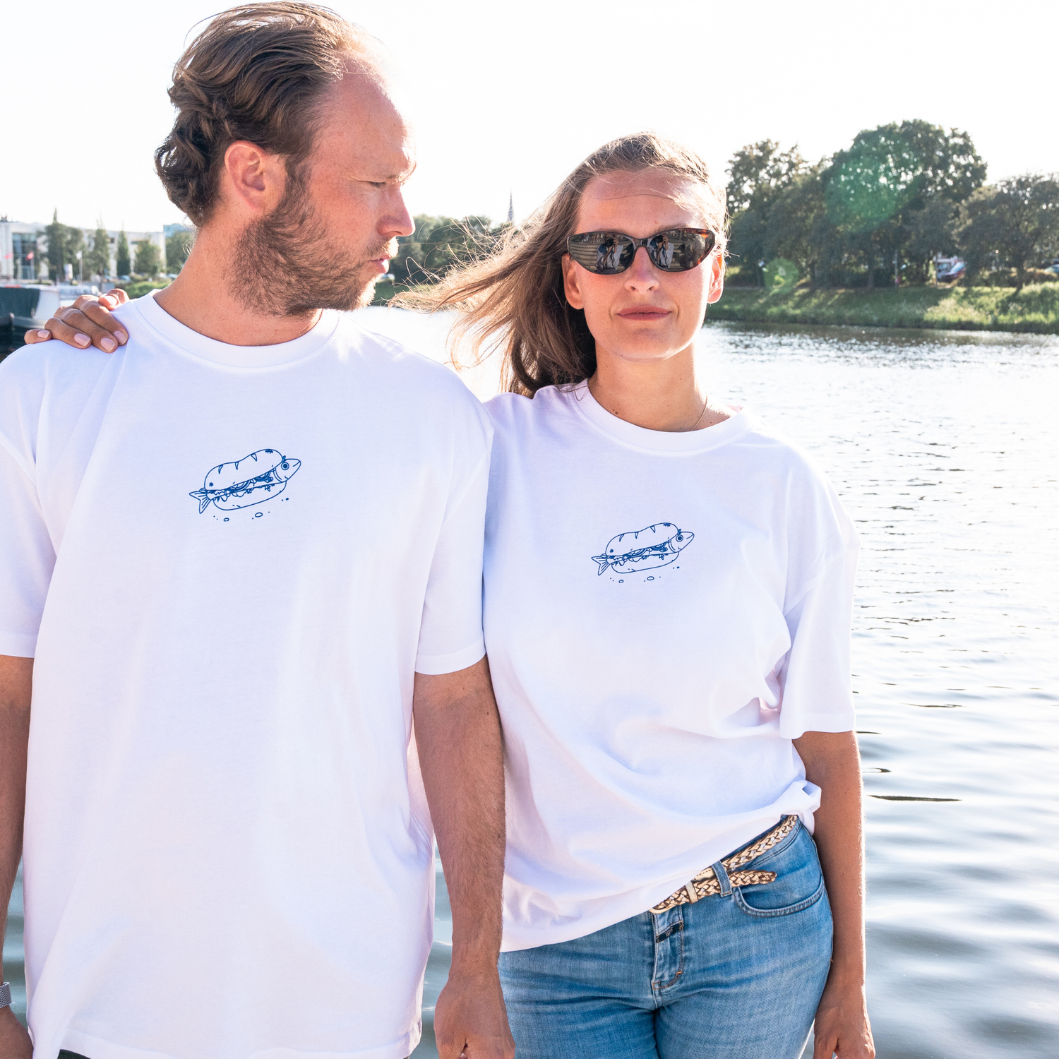 Paar mit Fischbrötchenclub T-Shirts vor dem Wasser in Lübeck