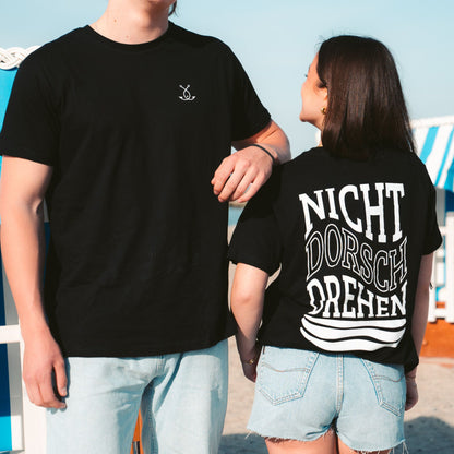 Schwarzes T-Shirt NICHT DORSCHDREHEN von Fangfrisch – Front- und Rückseite getragen am Strand