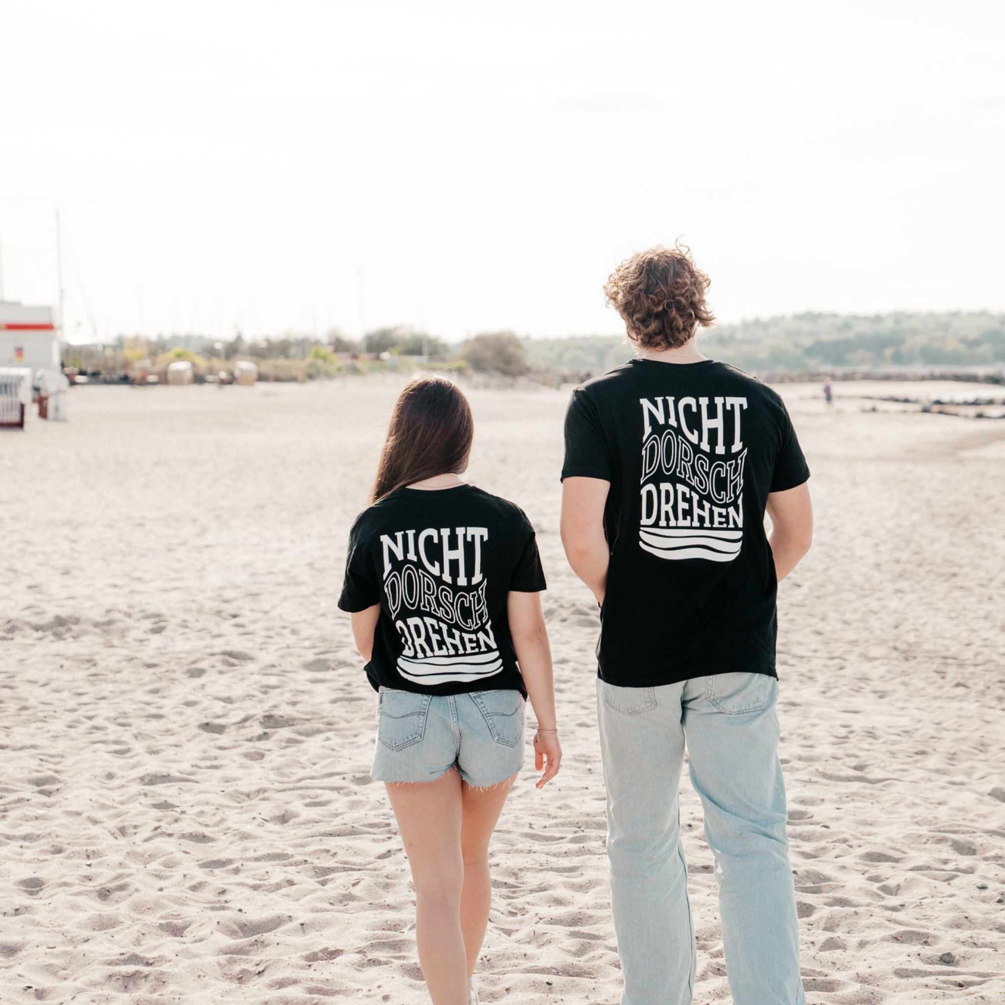 Zwei Personen am Strand mit T-Shirt NICHT DORSCHDREHEN – nordischer Lifestyle Look